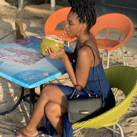 Candice drinking coconut on the beach.